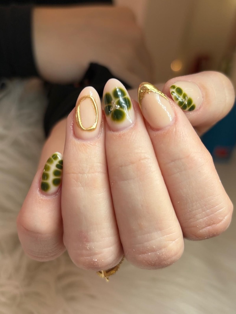 Manicura nude con arte verde y aros dorados