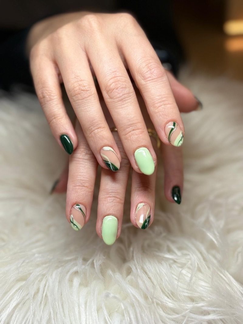 Uñas cortas en tonos verdes con líneas onduladas